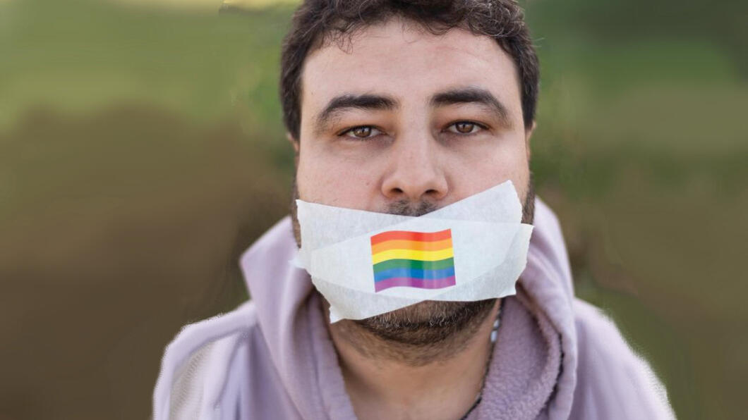 Persoon met mondkapje met regenboogvlag, logo LGBT Asylum Support. Origineel van de foto: Lisa van den Berg